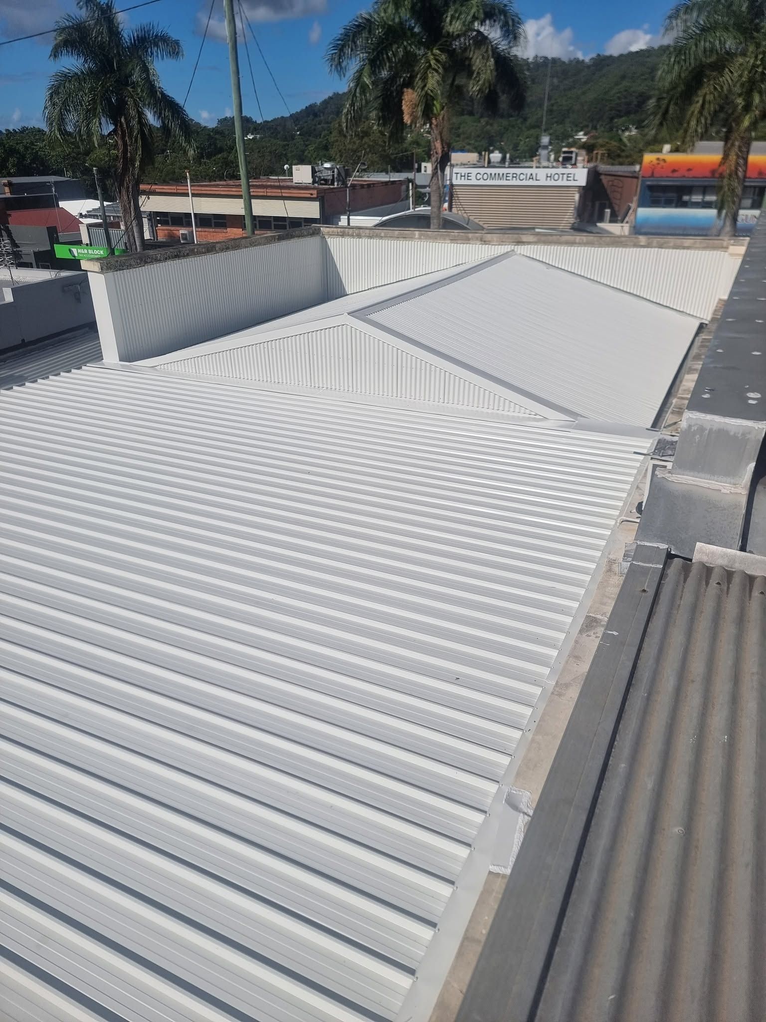 White Corrugated Metal Roof With a Sloped Skylight Under a Sunny Blue Sky — Stormguard Roofing In Caloundra West, QLD
