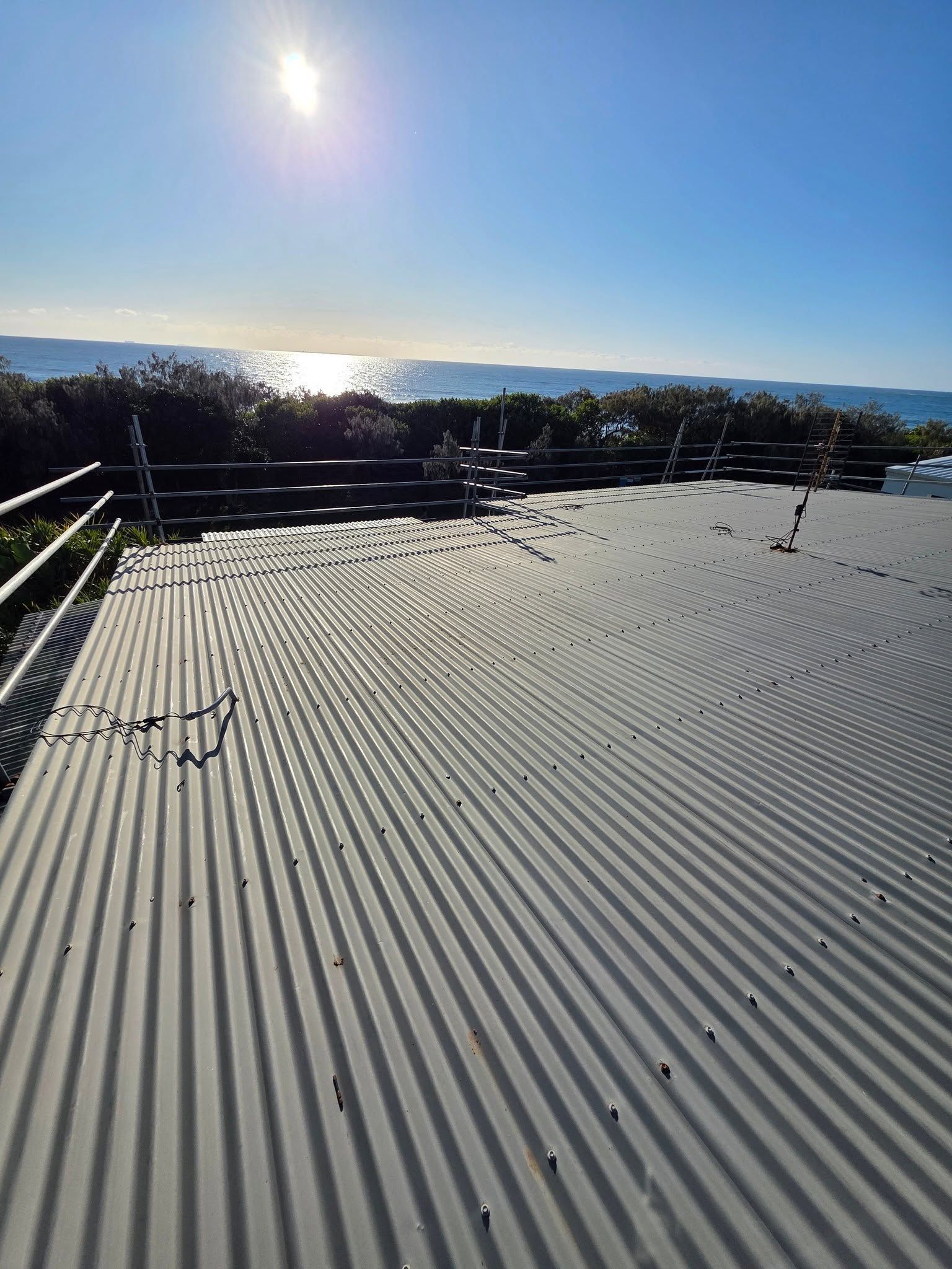 Rooftop Deck With Metal Railing Overlooking a Sunny Coastal Landscape — Stormguard Roofing In Caloundra West, QLD