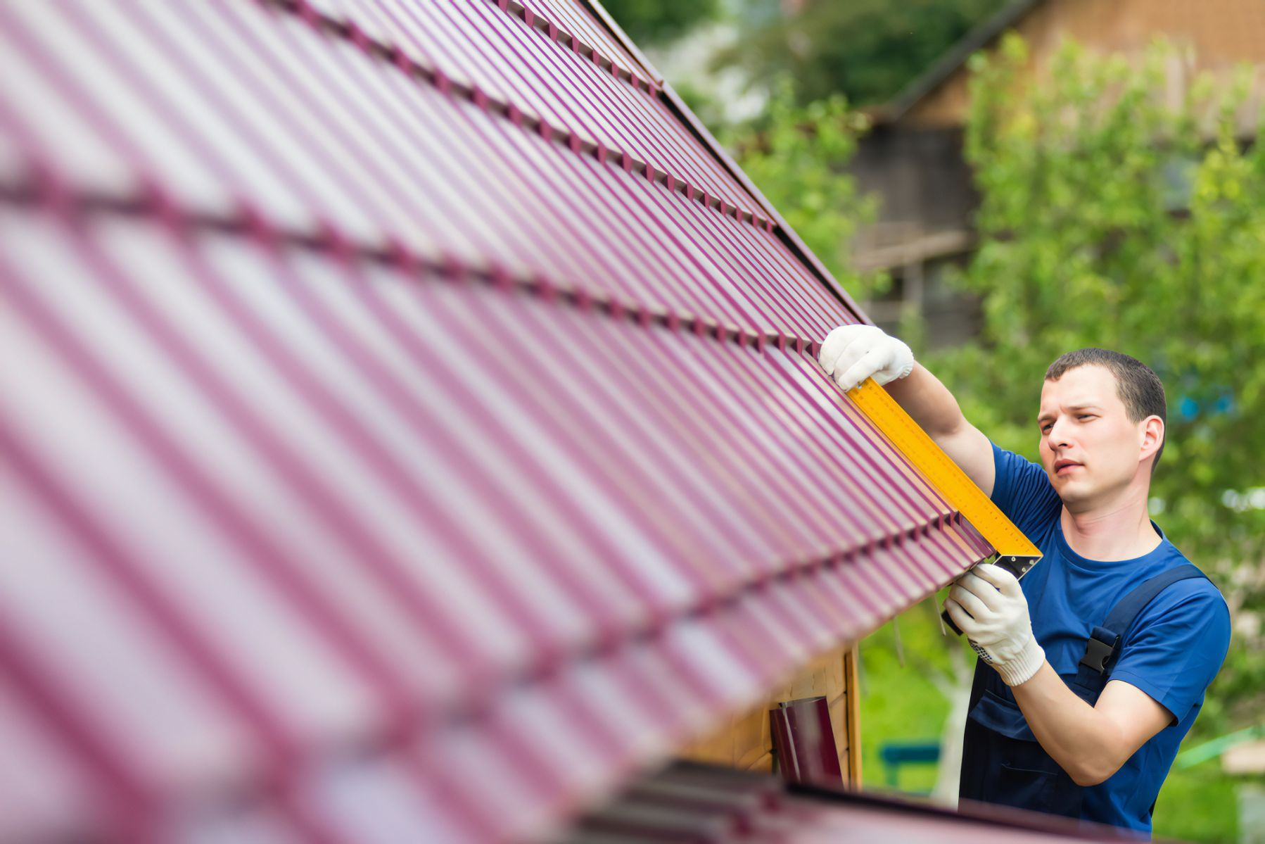 A Man is Installing a Metal Roof on a House — Stormguard Roofing In Caloundra West, QLD
