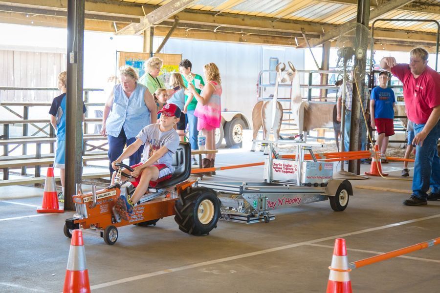 Go-kart race in a barn, with people watching behind safety cones and barriers