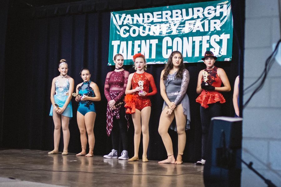 Five dancers pose onstage under a Vanderburgh County Fair talent contest banner.
