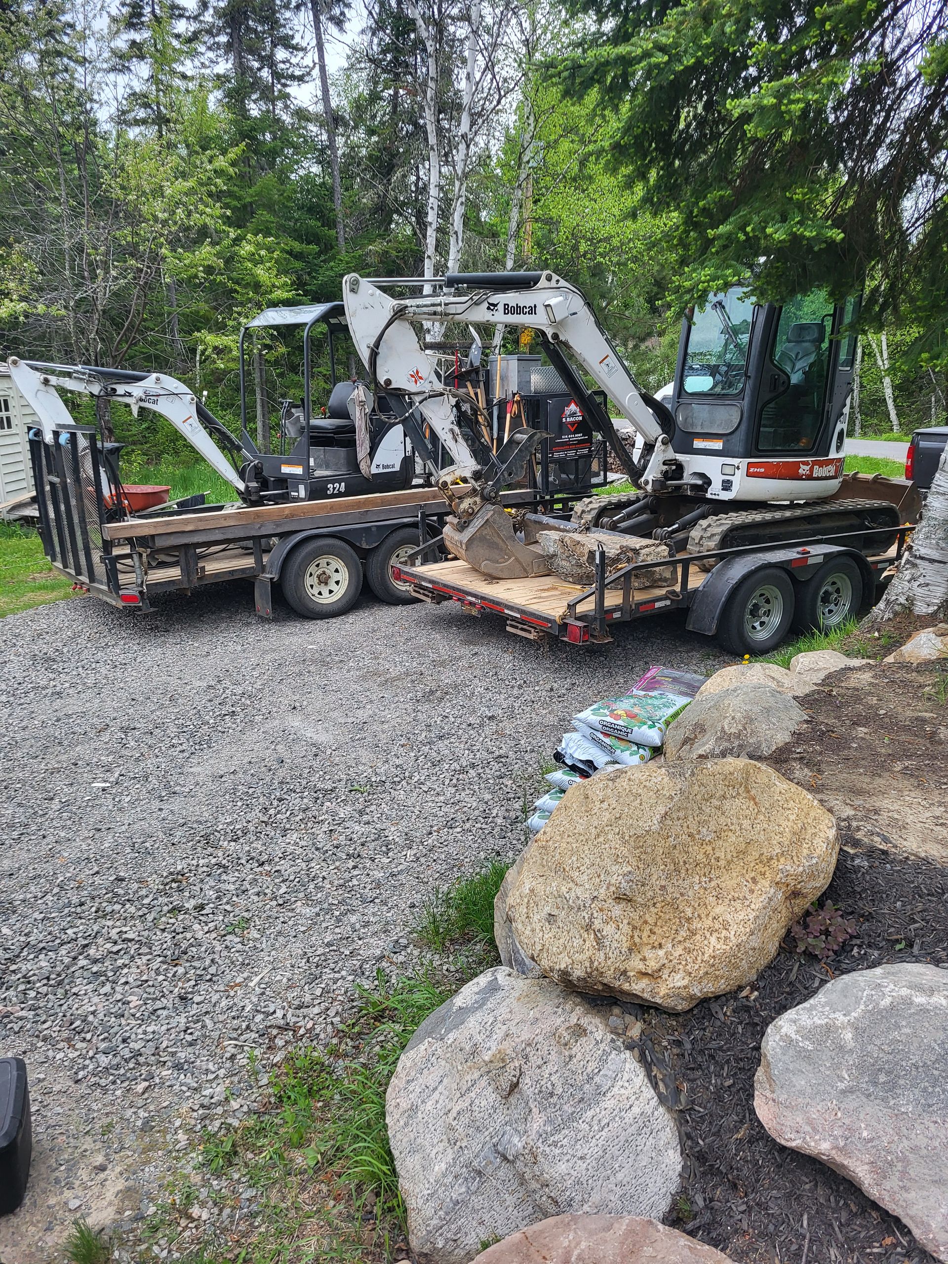 Un bulldozer et une remorque sont garés sur un chemin de gravier.