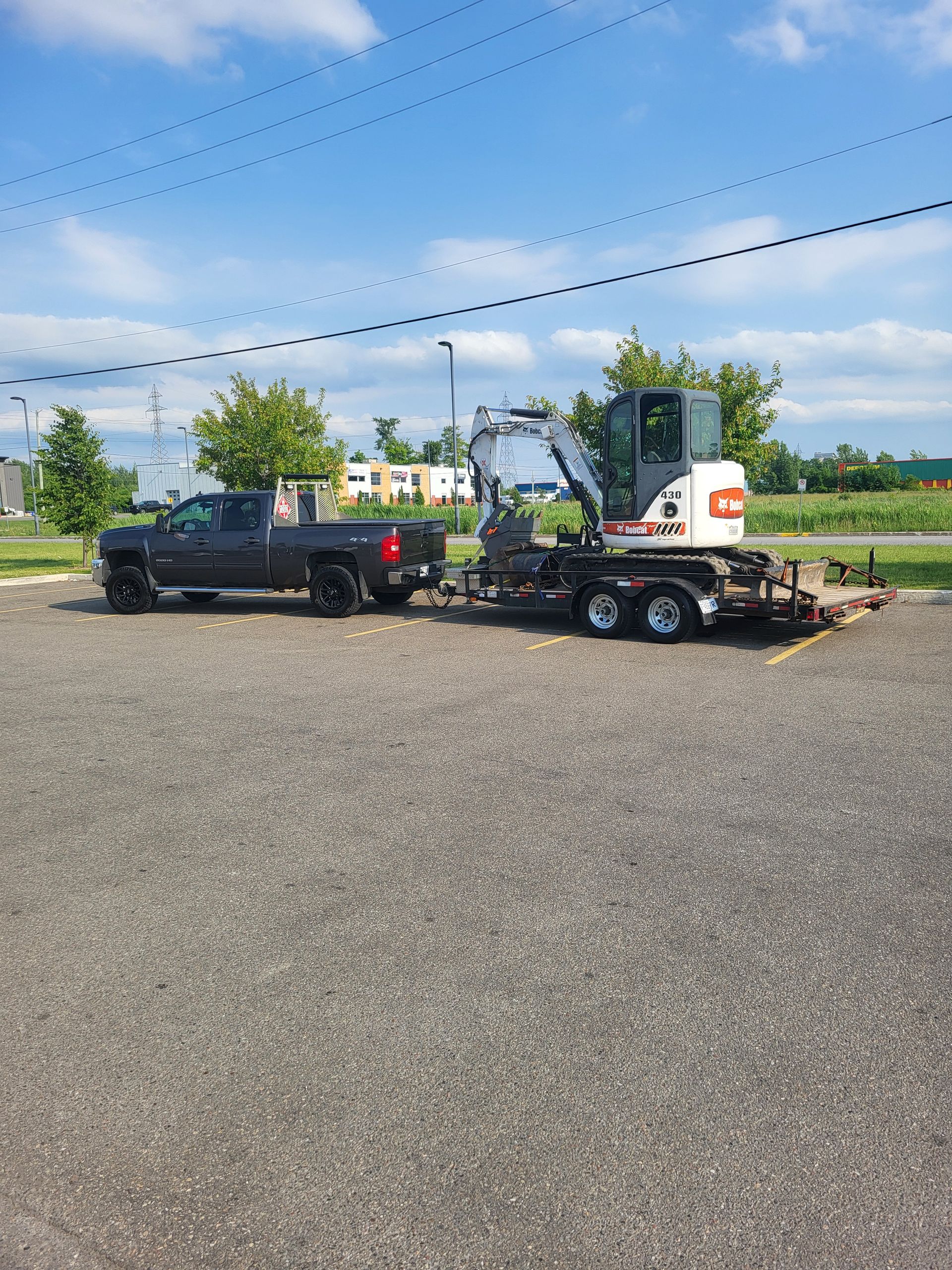 Un camion remorque une petite excavatrice sur une remorque.