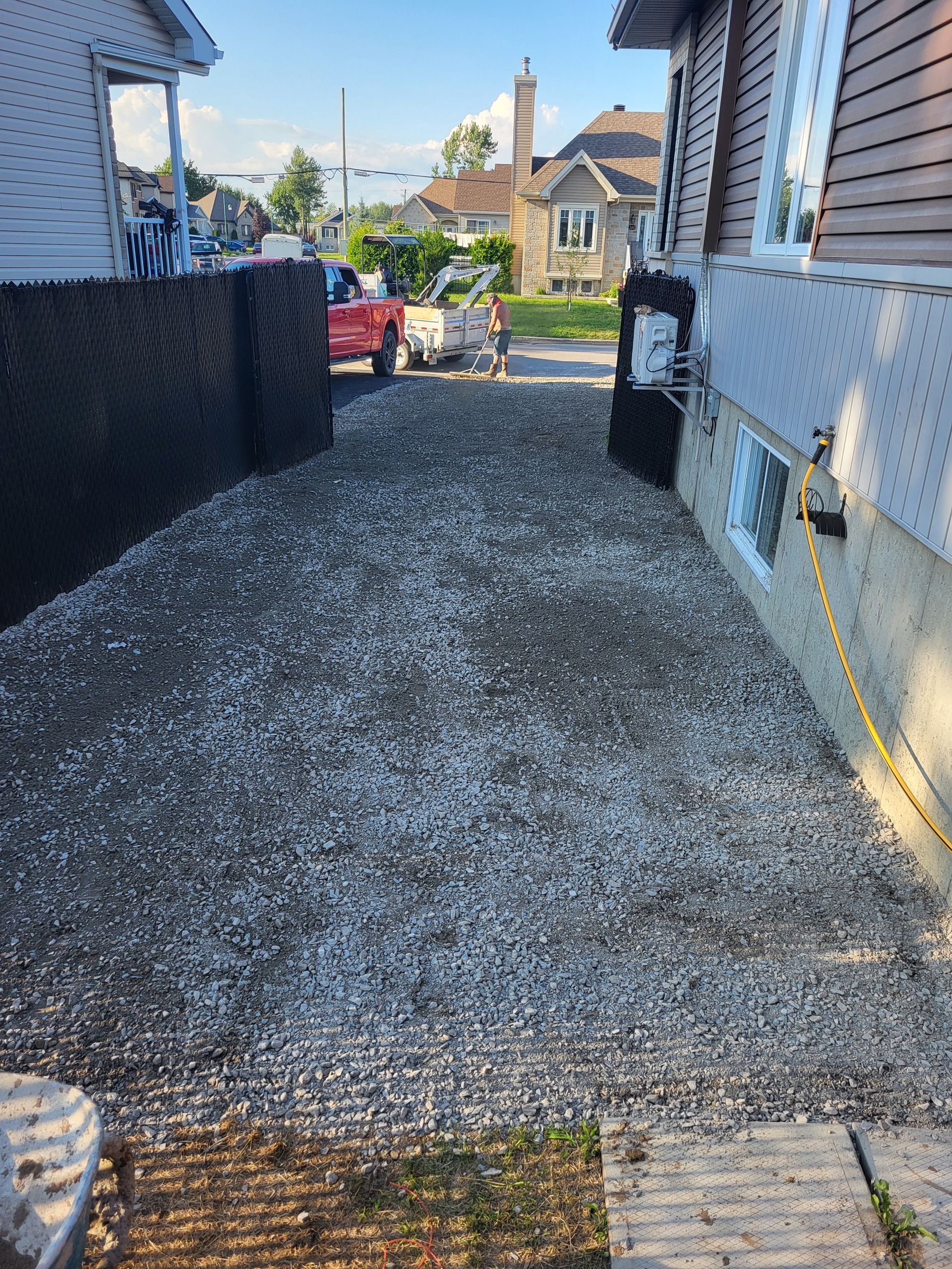 Un tracteur est garé dans une allée de gravier à côté d'une maison.