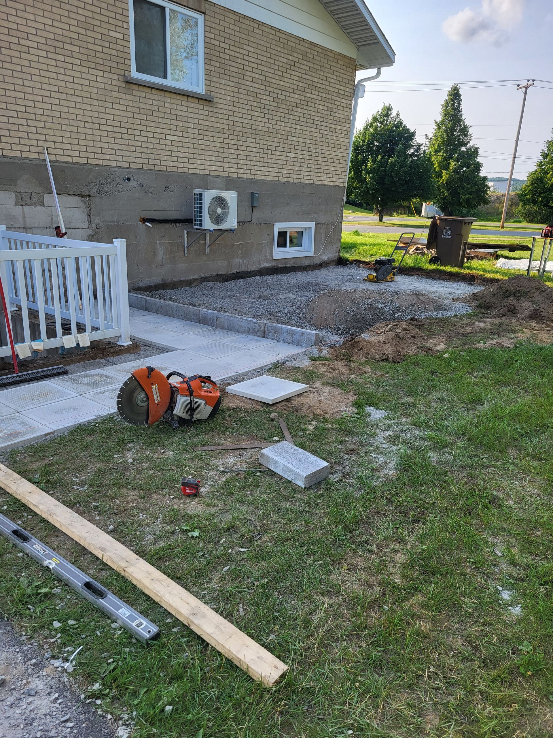 Une maison est en cours de rénovation et un patio est en cours de construction devant elle.