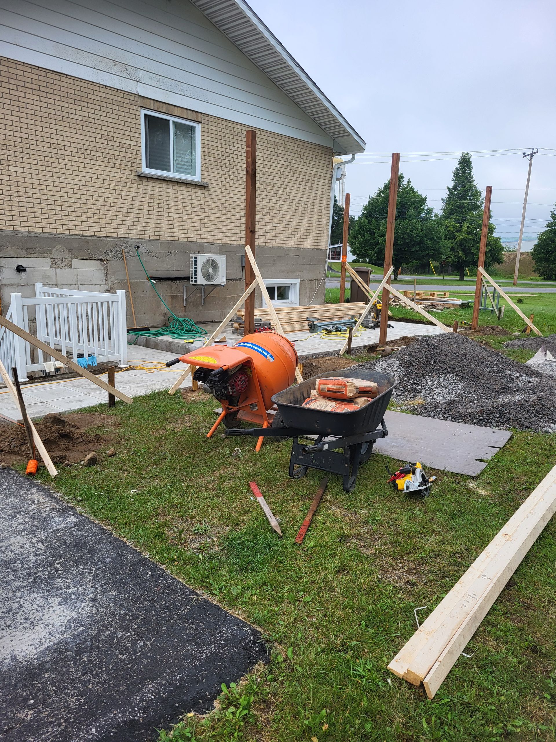 Une brouette est assise devant une maison en construction.
