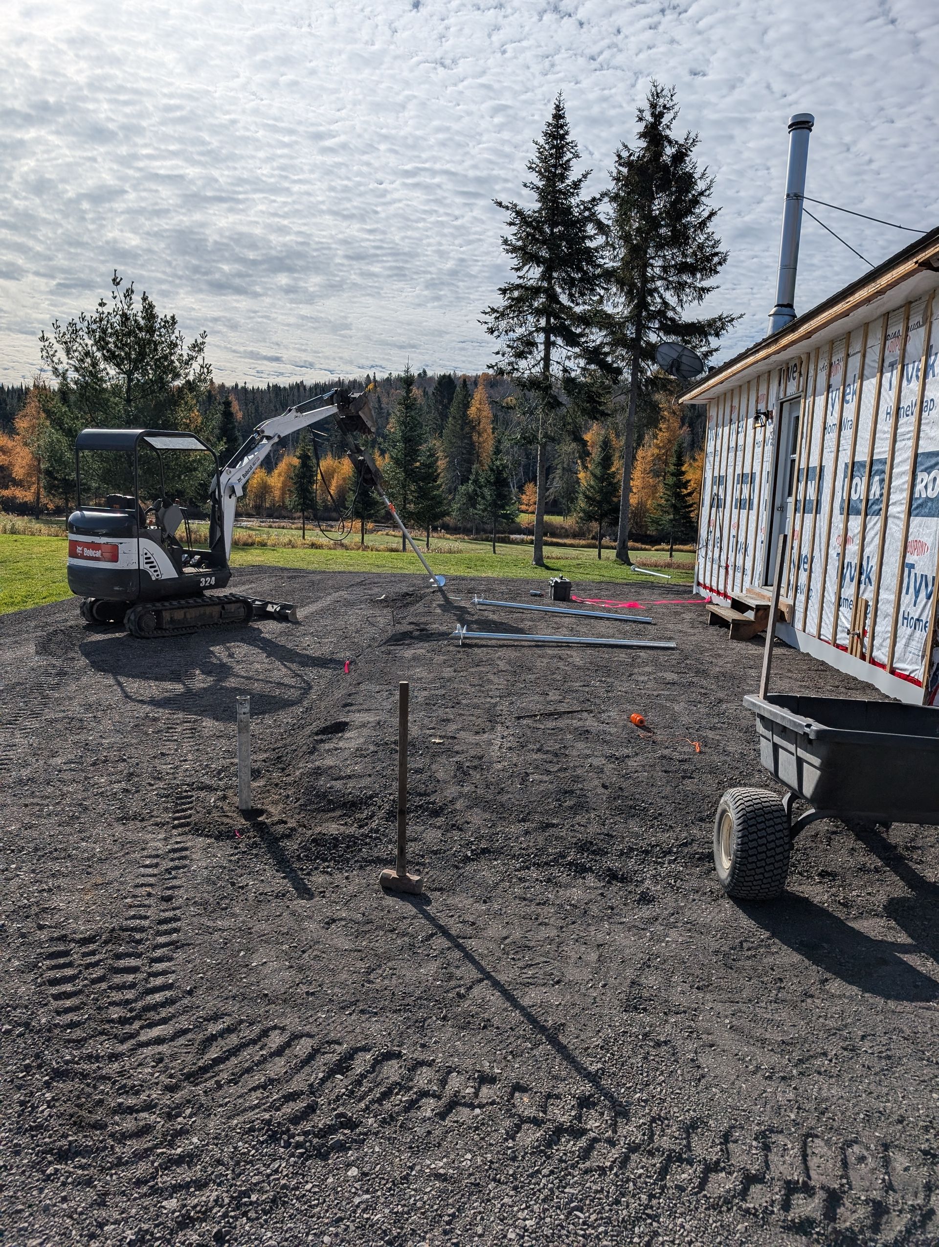 Une petite excavatrice est assise devant une maison en construction.