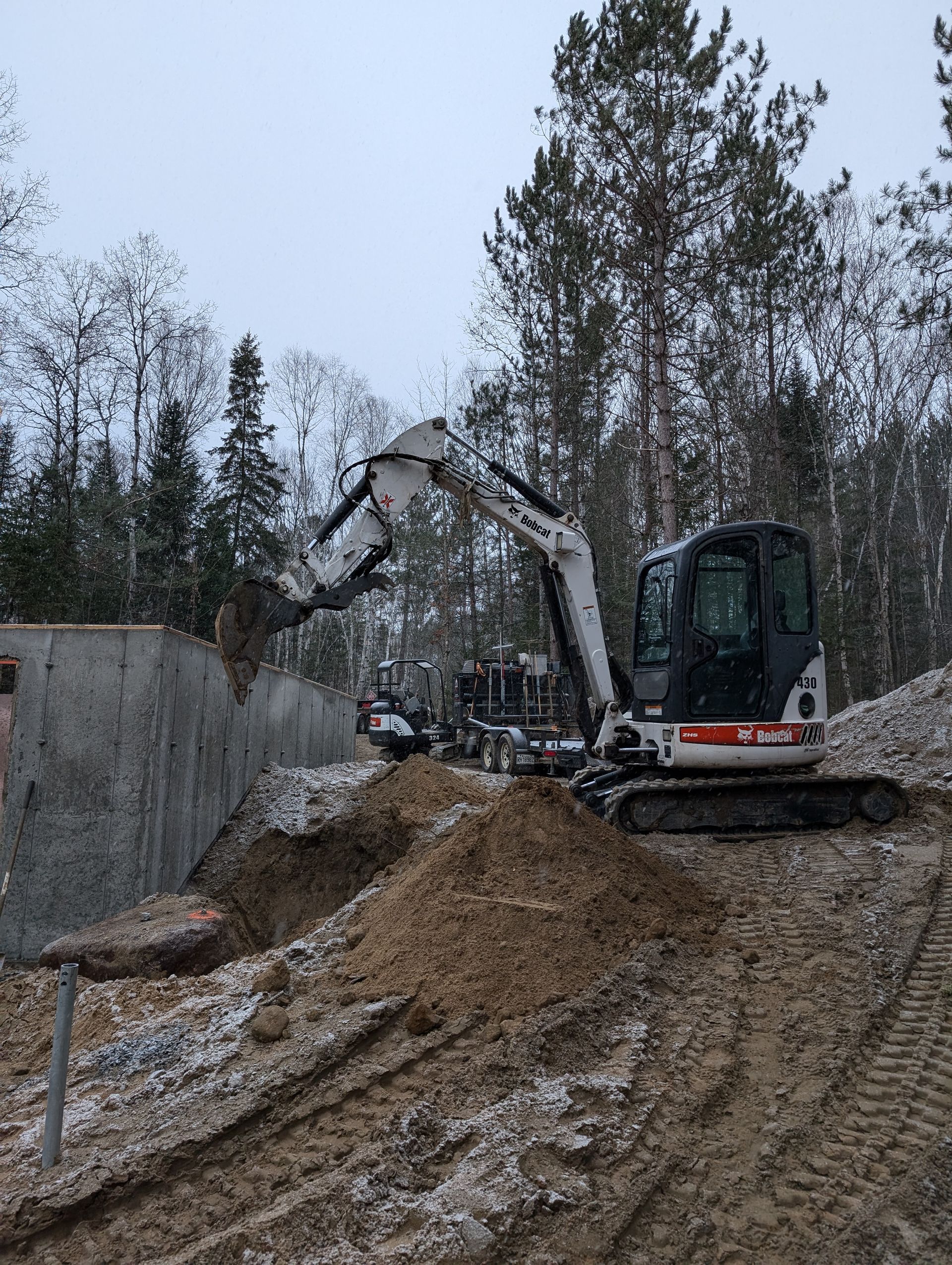 Une petite excavatrice creuse un trou dans le sol.