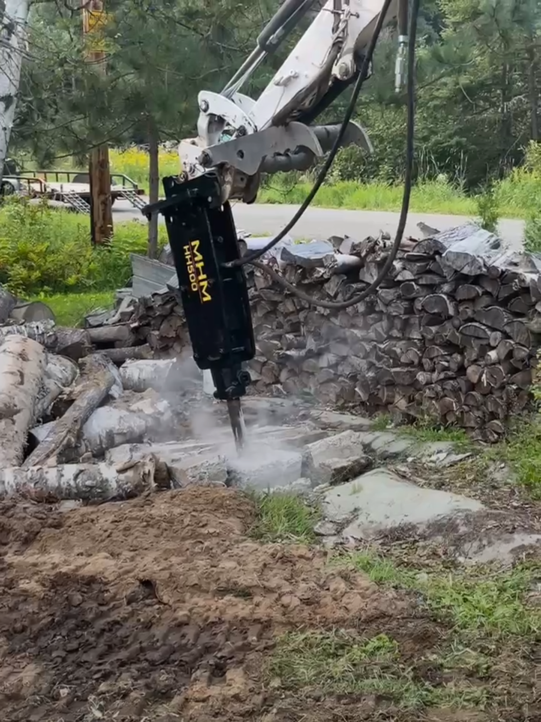 Un marteau hydraulique est utilisé pour briser un mur de pierre.