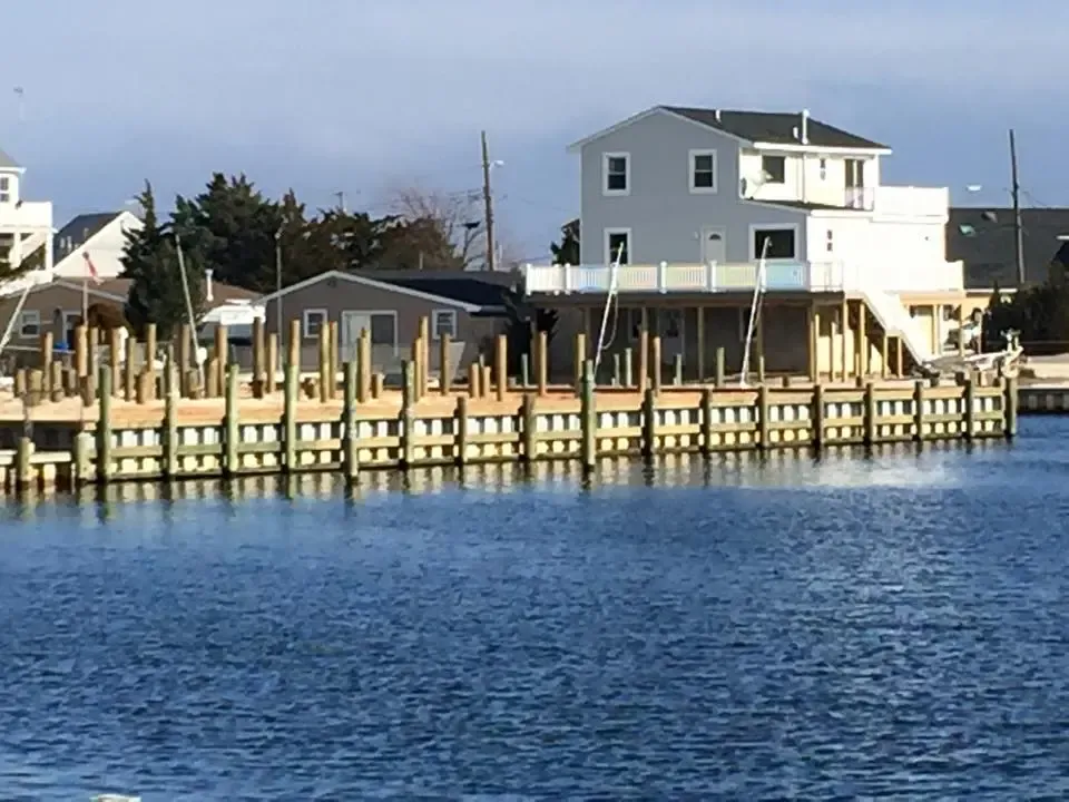 A house is sitting on top of a body of water next to a dock.