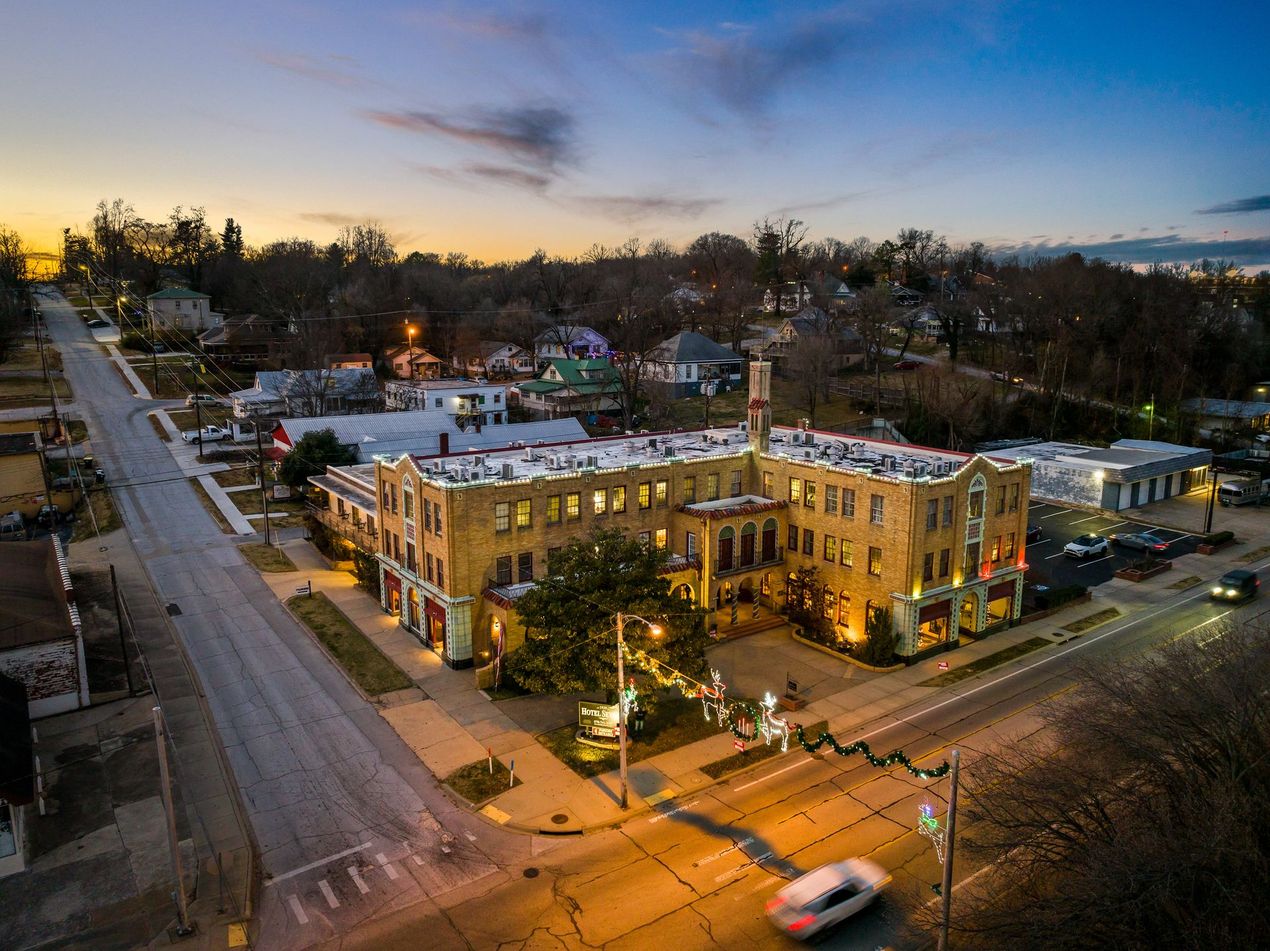 Aerial view of a multi-story brick building at dusk, with a street and trees in a neighborhood.