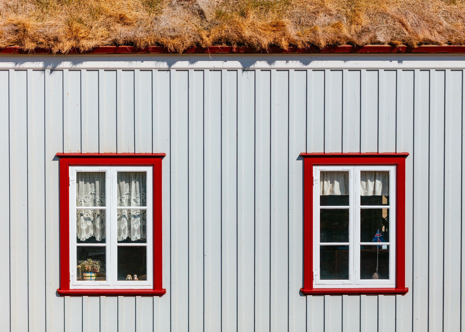 A white house with two windows and a thatched roof