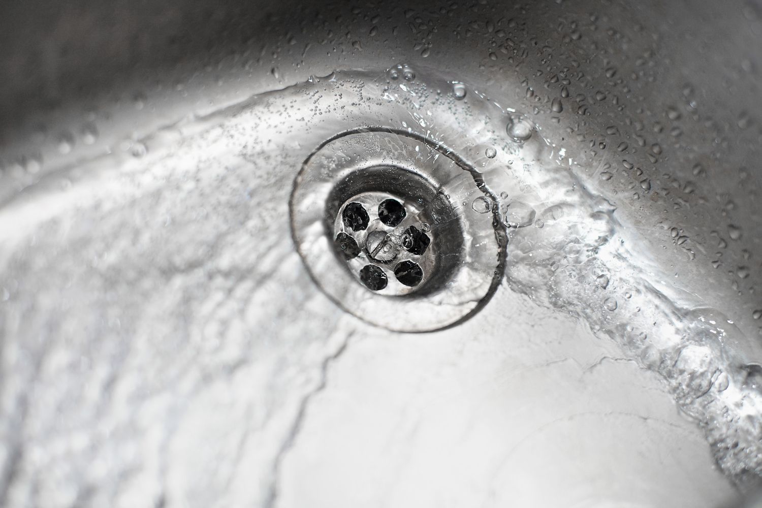 A close up of a sink with water running down the drain.