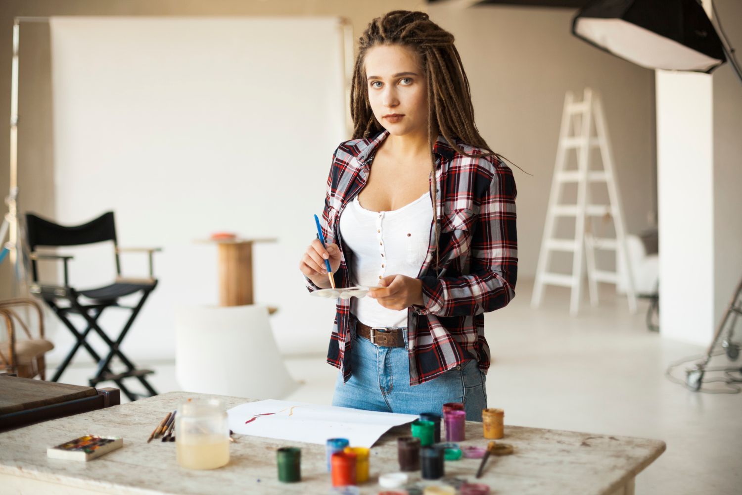 A woman is standing at a table holding a brush and painting.