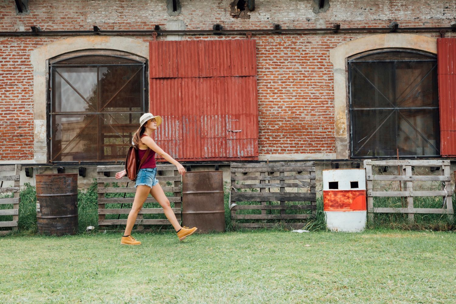 A woman is walking in front of a brick building.