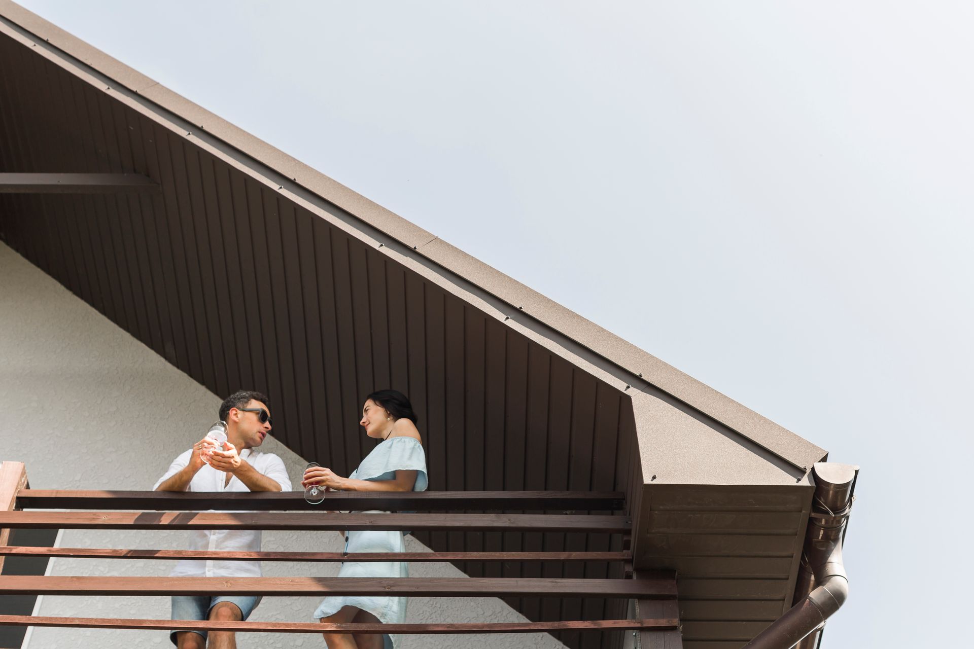 A man and a woman are standing on a balcony of a house.