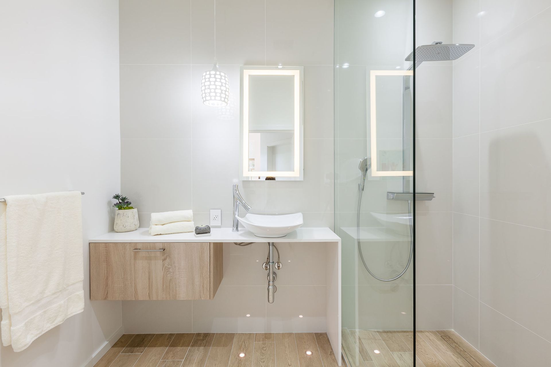 A bathroom with a sink , mirror and walk in shower.