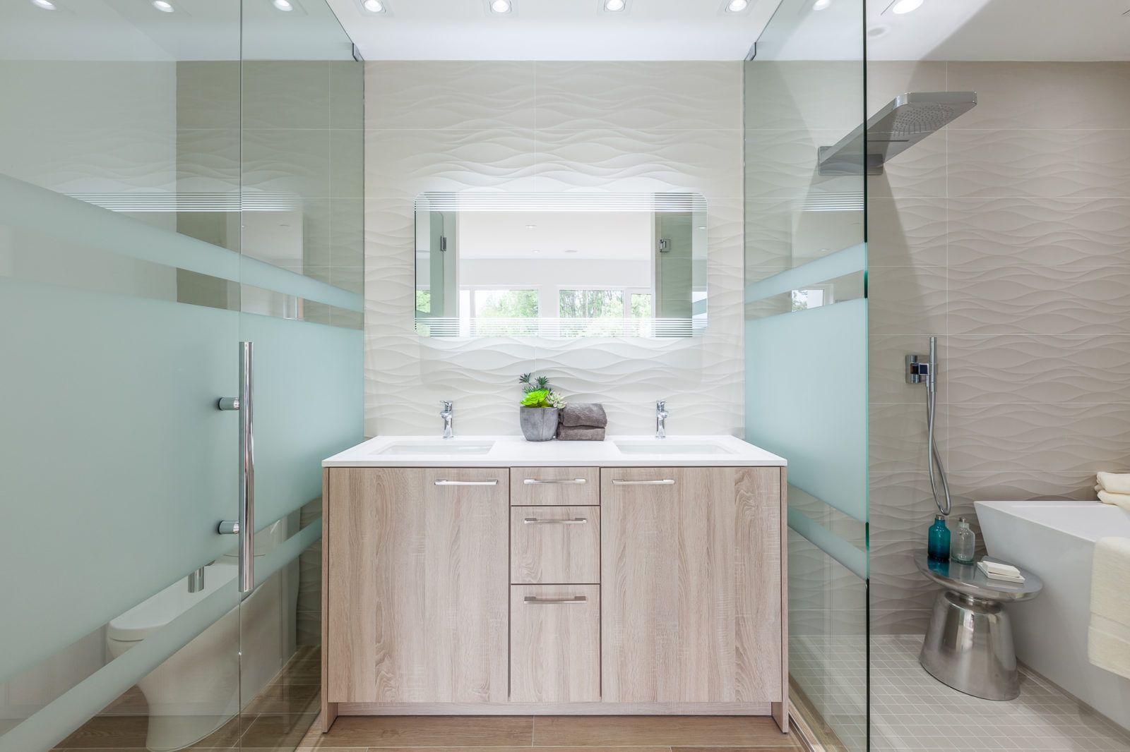 A bathroom with two sinks , a toilet , and a walk in shower.