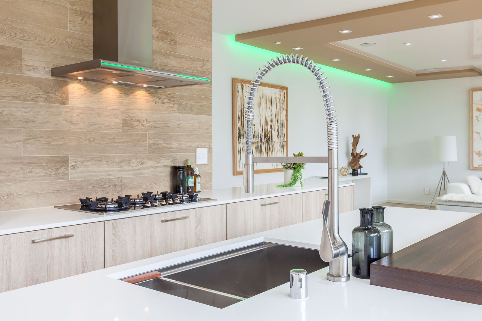 A kitchen with a sink , stove , hood and a faucet.