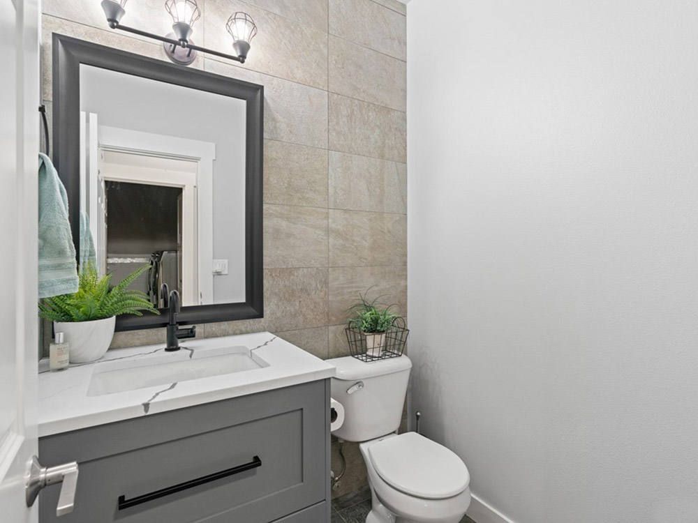 A bathroom with a sink , toilet and mirror.