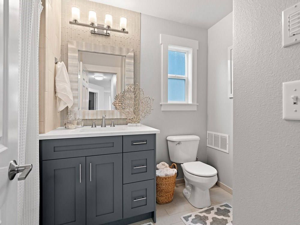 A bathroom with a sink , toilet , mirror and window.