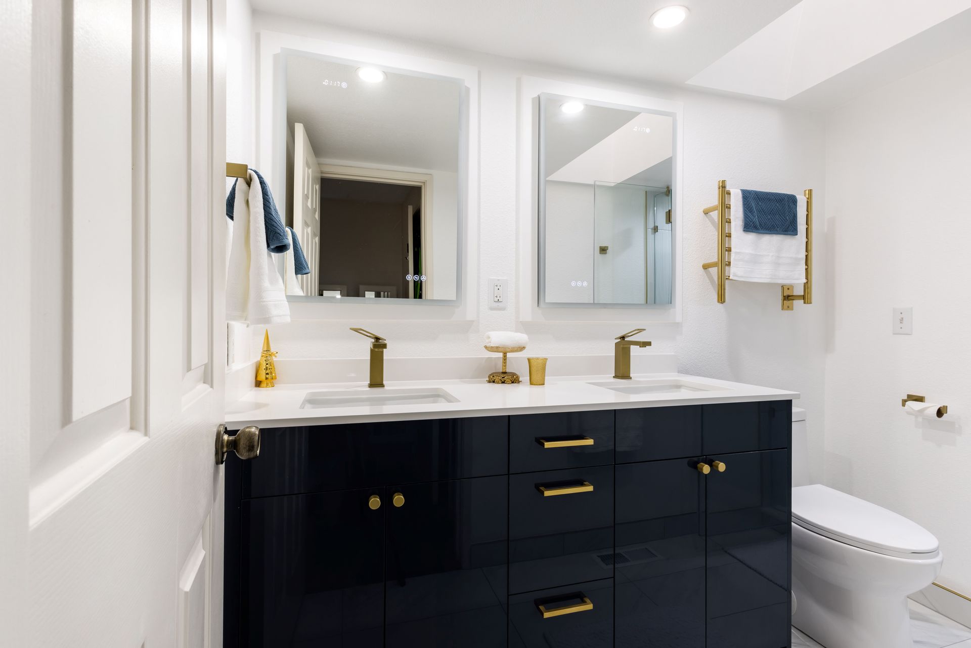 A bathroom with two sinks , two mirrors and a toilet.
