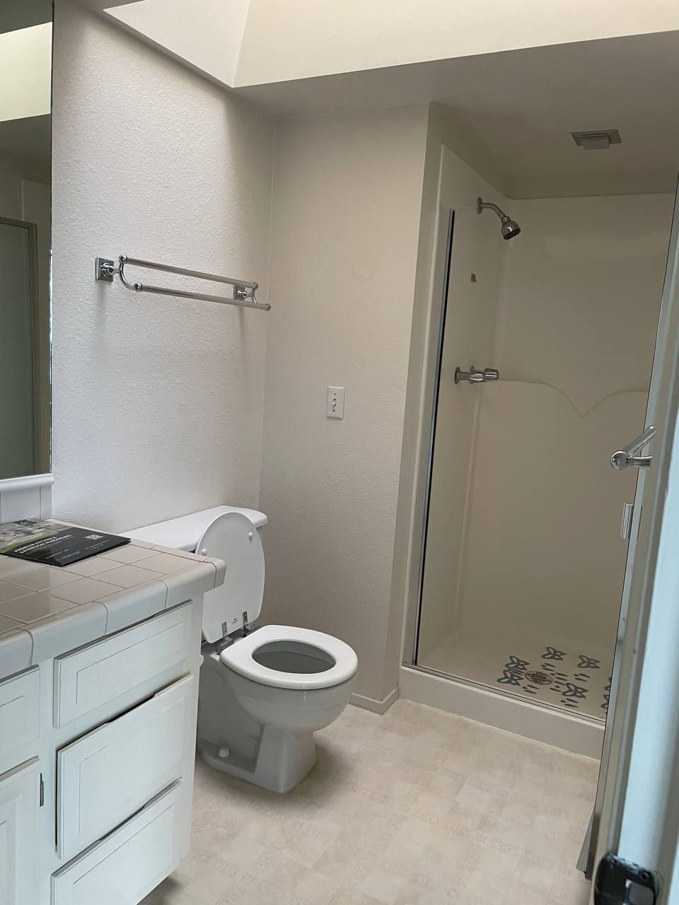 A bathroom with a toilet , sink and shower.