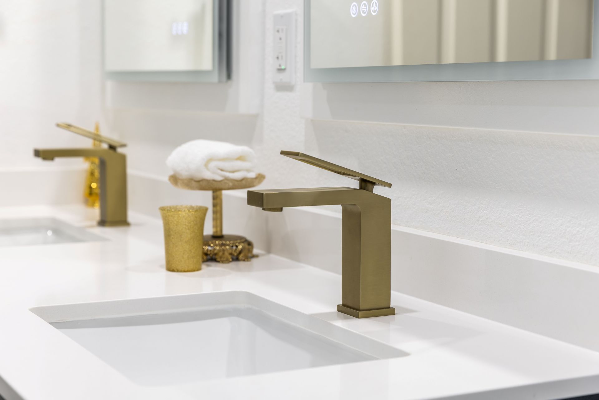 There are two sinks in the bathroom with gold faucets.