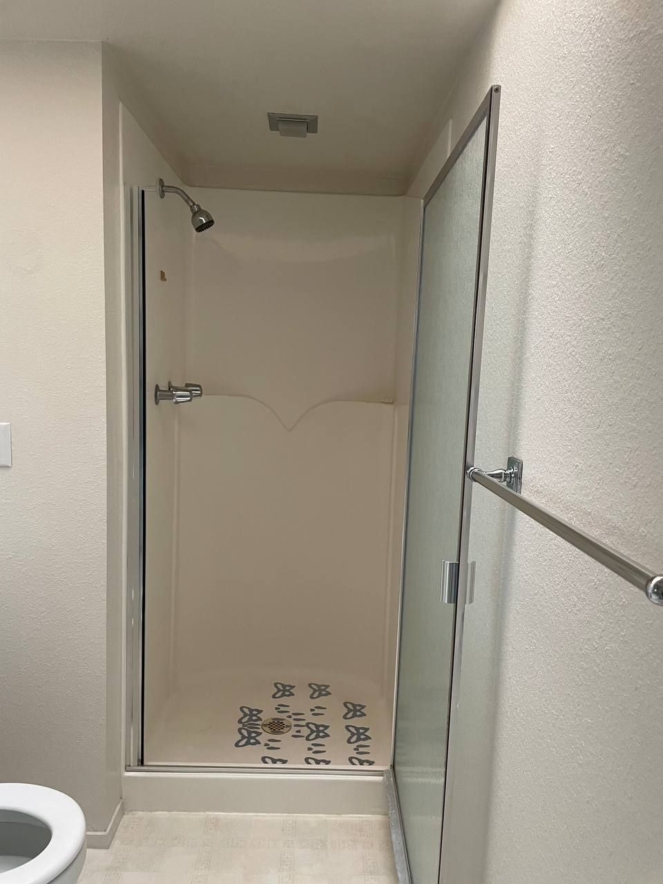 A bathroom with a toilet and a shower with a glass door.