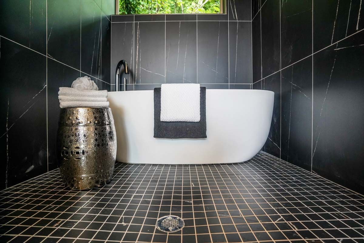 There is a bathtub in the bathroom with black tiles.