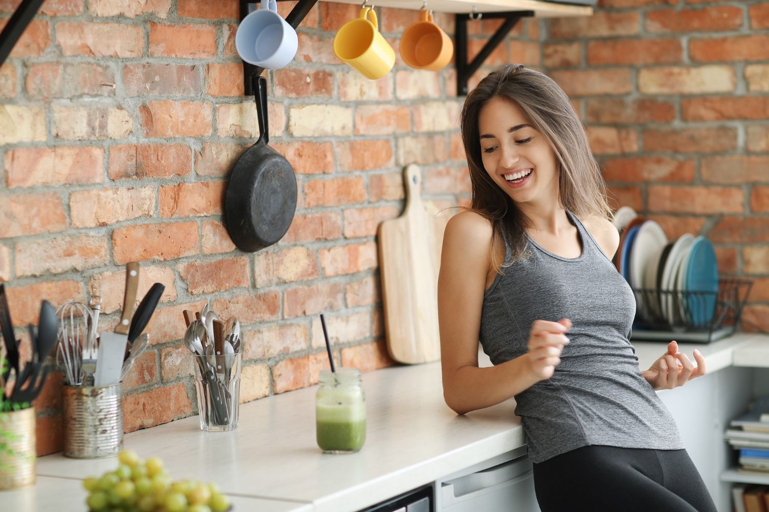 A woman is sitting on a counter in a kitchen.