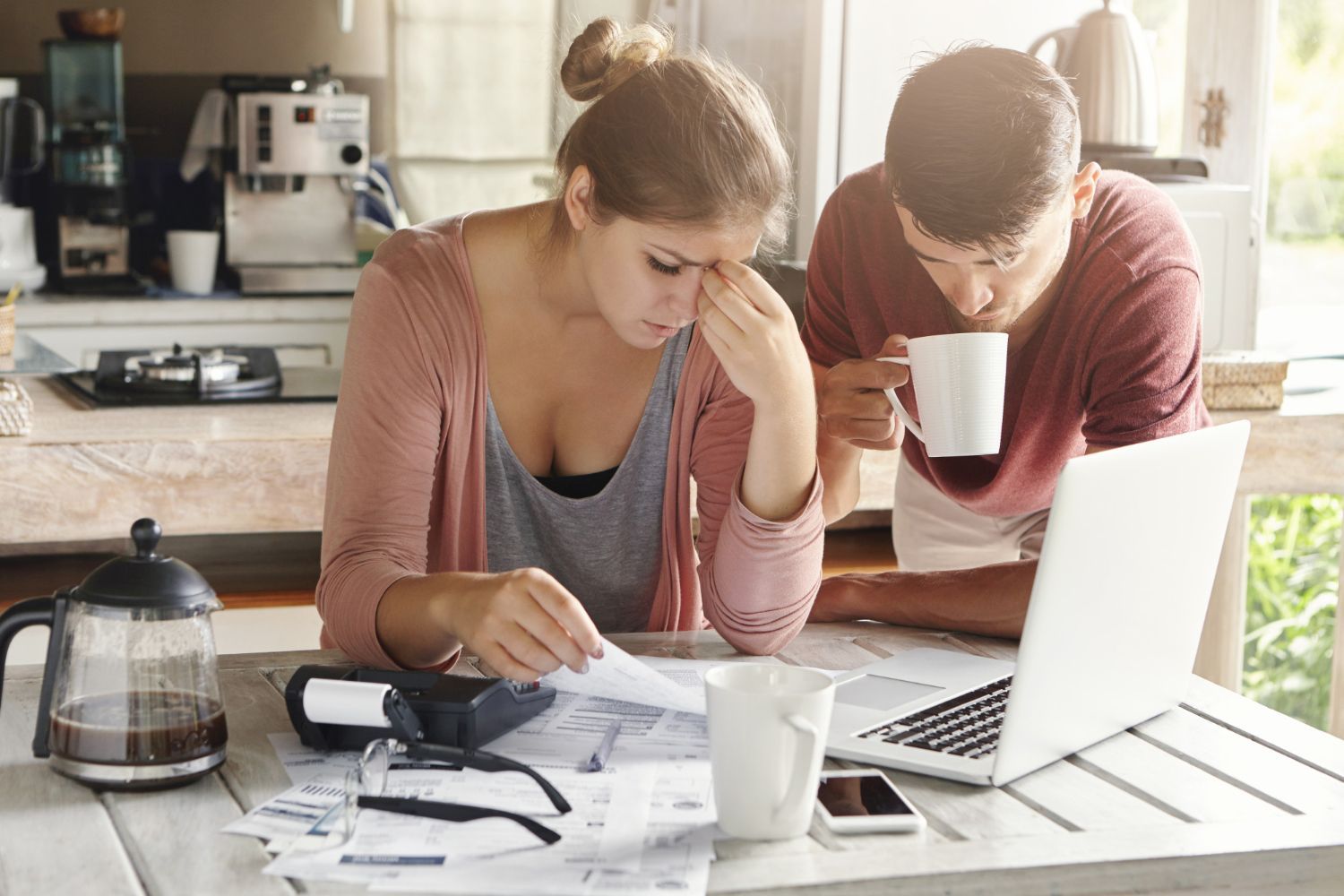 A man and a woman are sitting at a table with papers and a laptop.