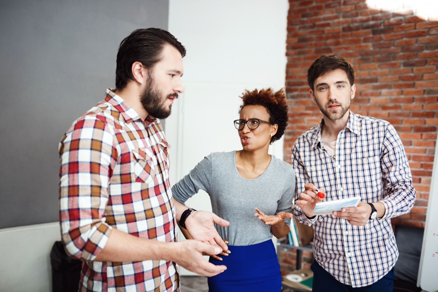 A group of people are standing in a room talking to each other.