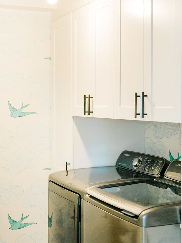 A laundry room with a washer and dryer and white cabinets.