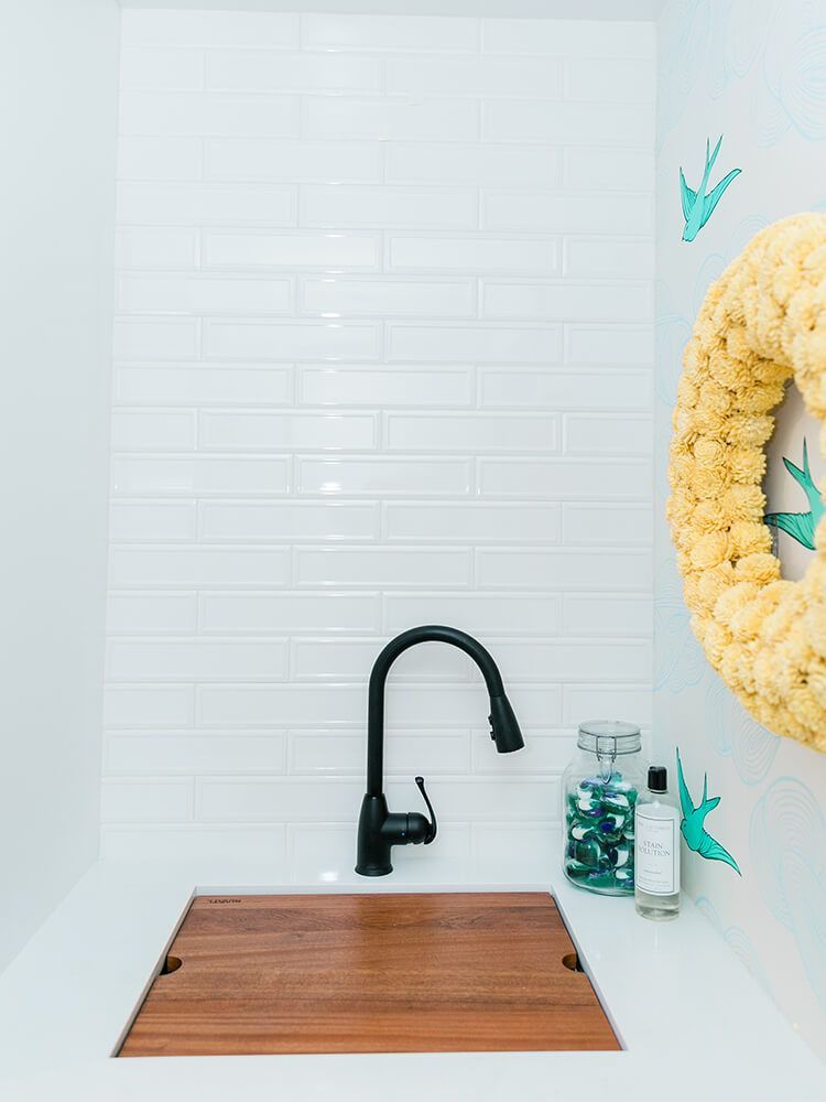 A bathroom sink with a black faucet and a wooden cutting board.