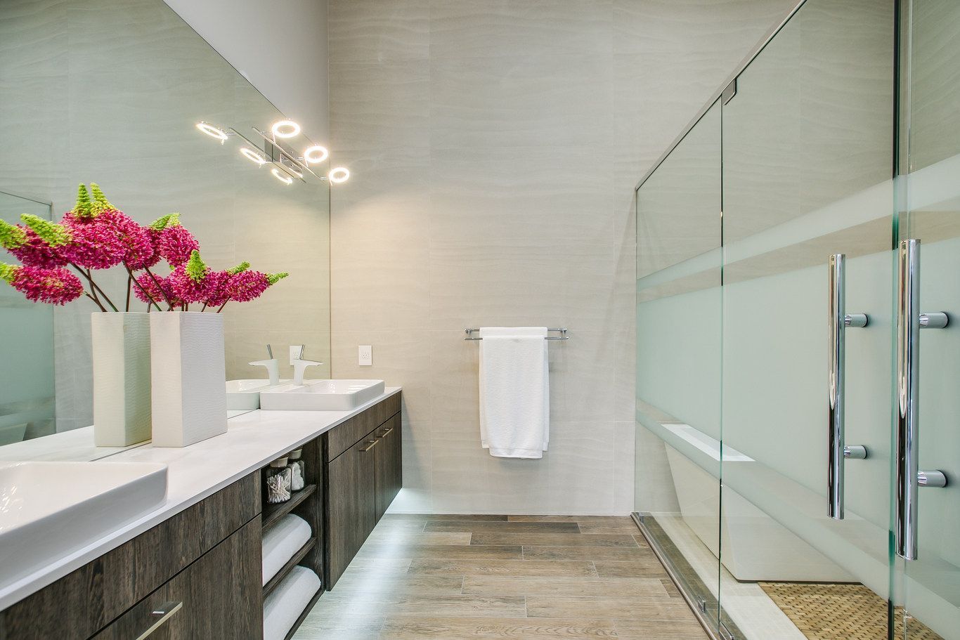 A bathroom with two sinks , a walk in shower and a large mirror.