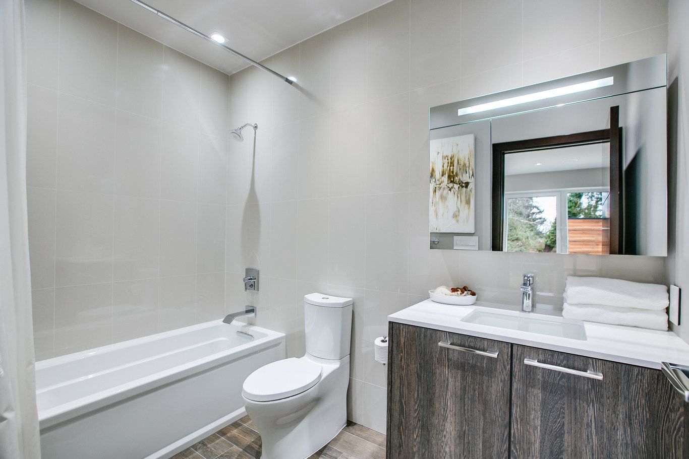 A bathroom with a toilet , sink , bathtub and mirror.