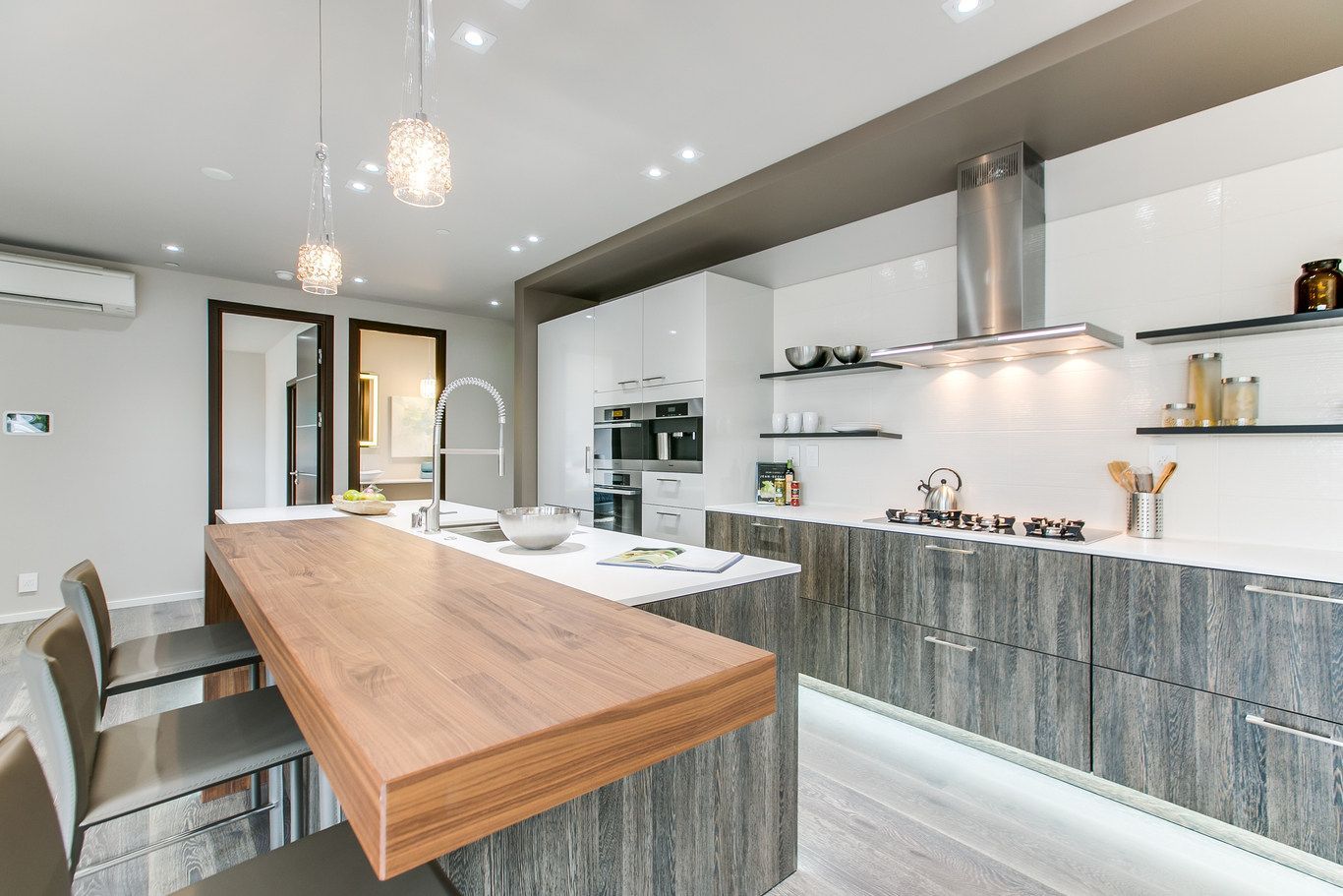 A kitchen with a long wooden counter top and stainless steel appliances.