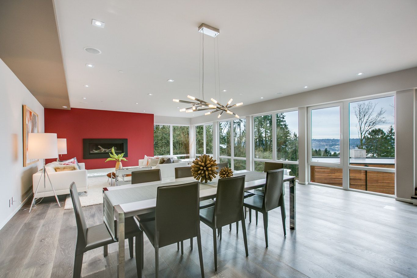 A large dining room with a table and chairs and a red wall.