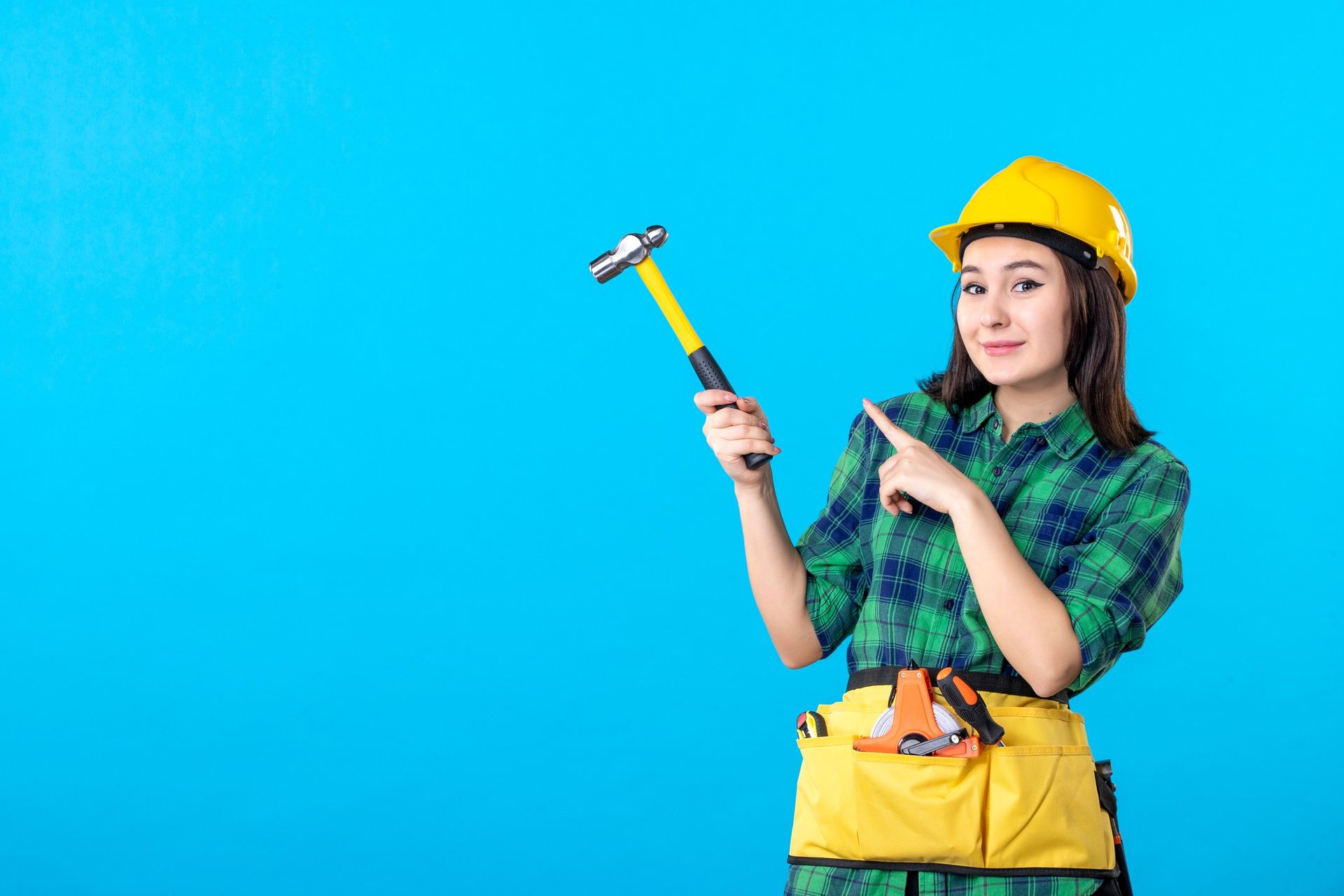 A woman is holding a hammer and pointing at it.