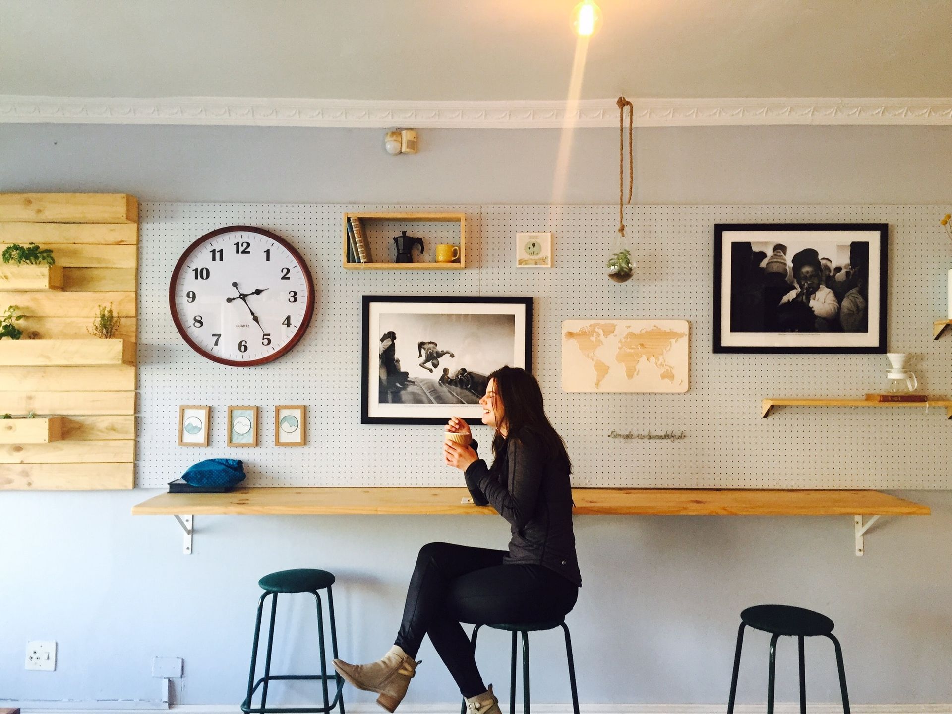A woman is sitting at a table with a clock on the wall above her