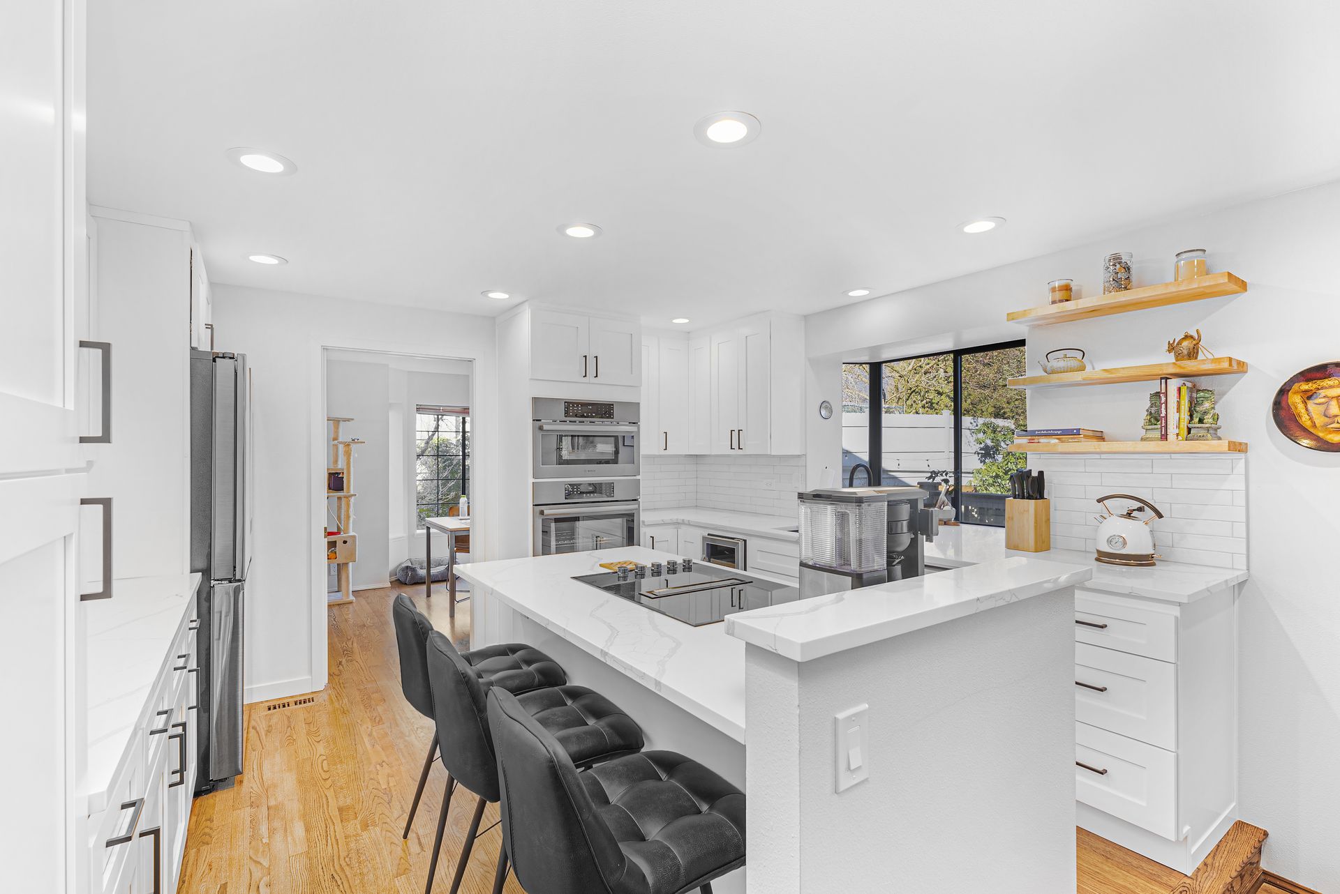 A kitchen with white cabinets , stainless steel appliances , and a large island.