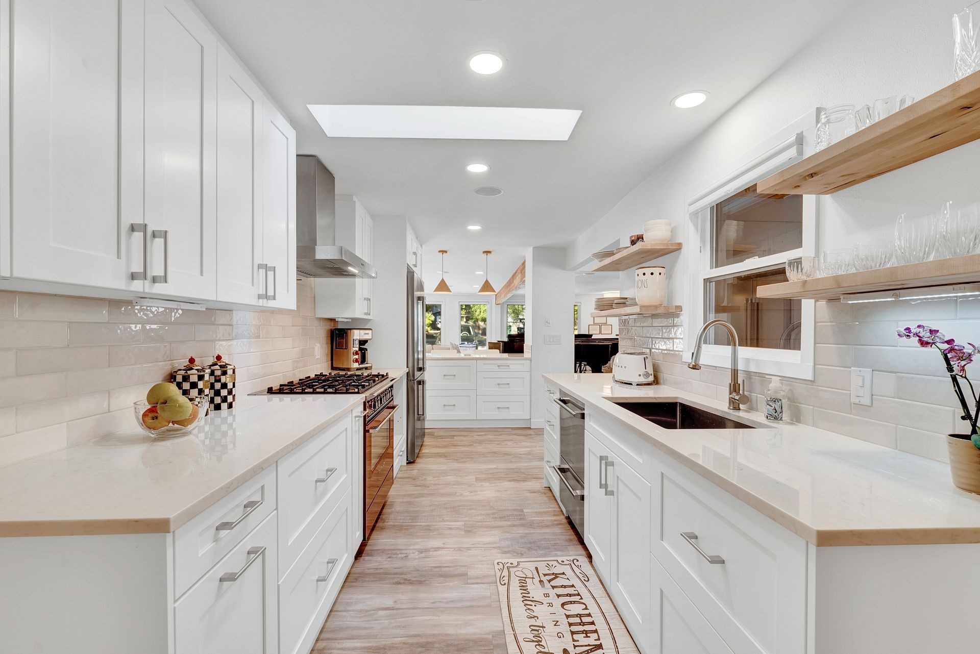 A kitchen with white cabinets , stainless steel appliances , and a skylight.