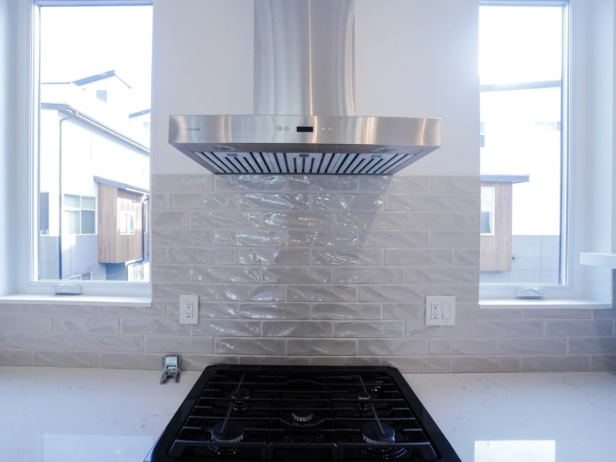 A kitchen with a stove top oven and a stainless steel hood.