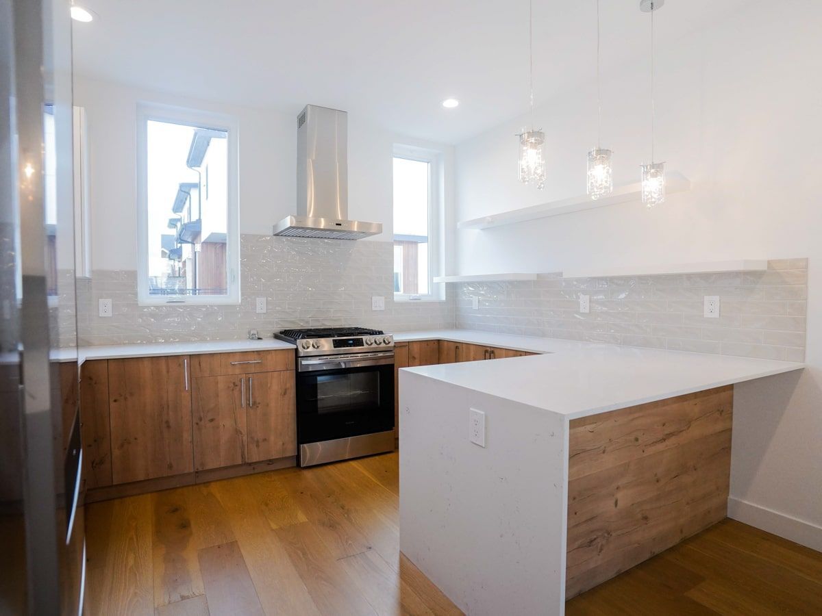A kitchen with stainless steel appliances , wooden cabinets , and white counter tops.