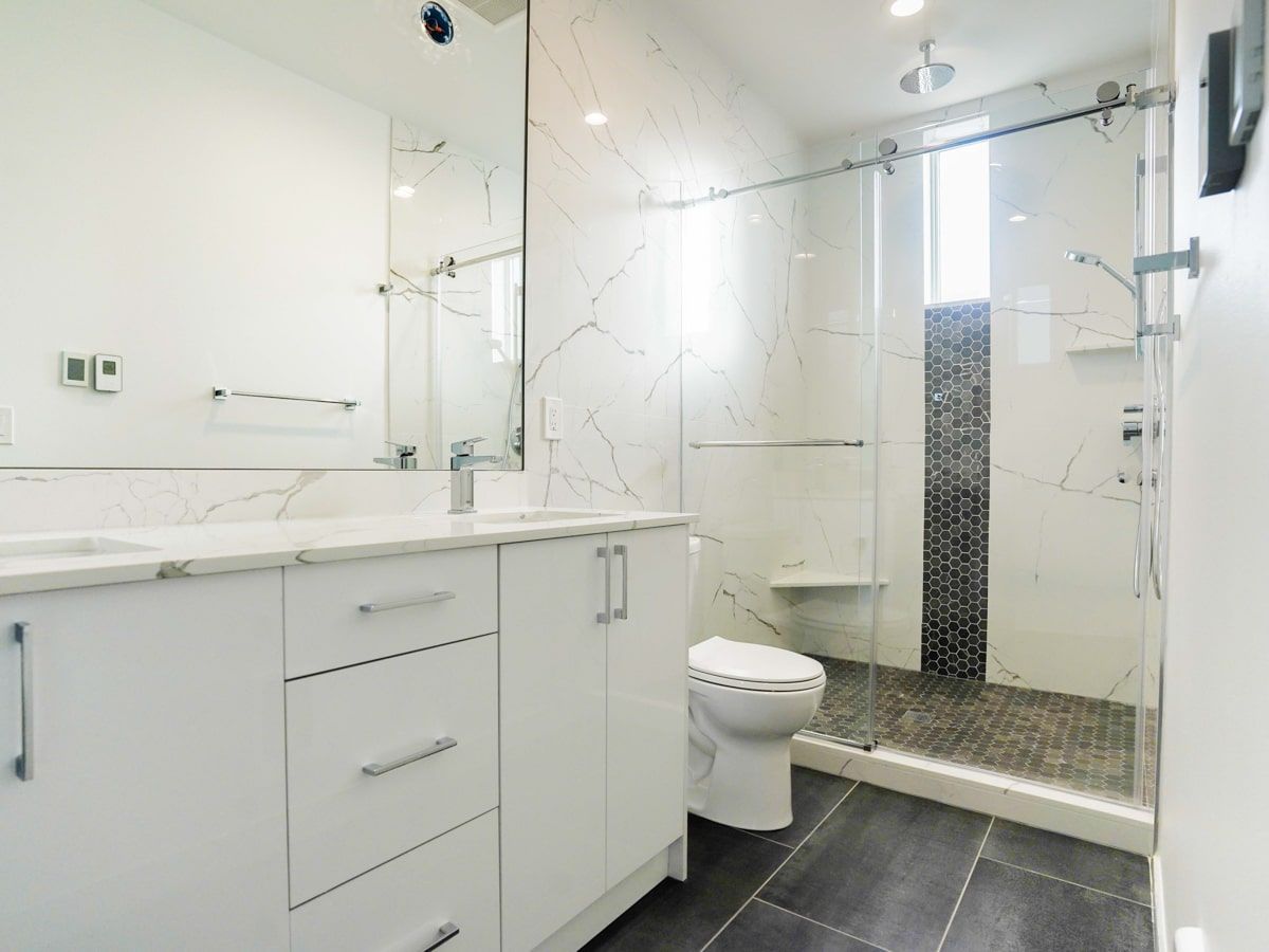 A bathroom with a toilet , sink , mirror and walk in shower.