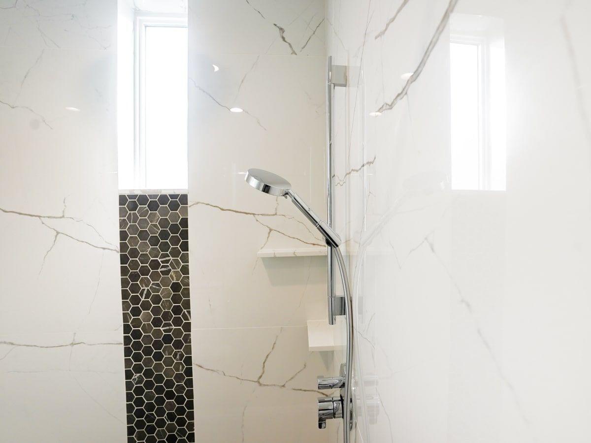 A bathroom with a shower head and a window.