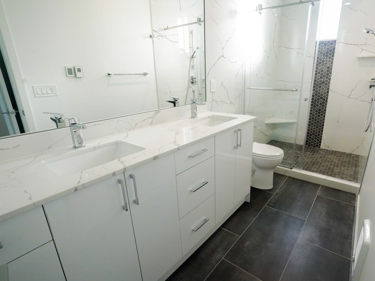 A bathroom with two sinks , a toilet , and a walk in shower.