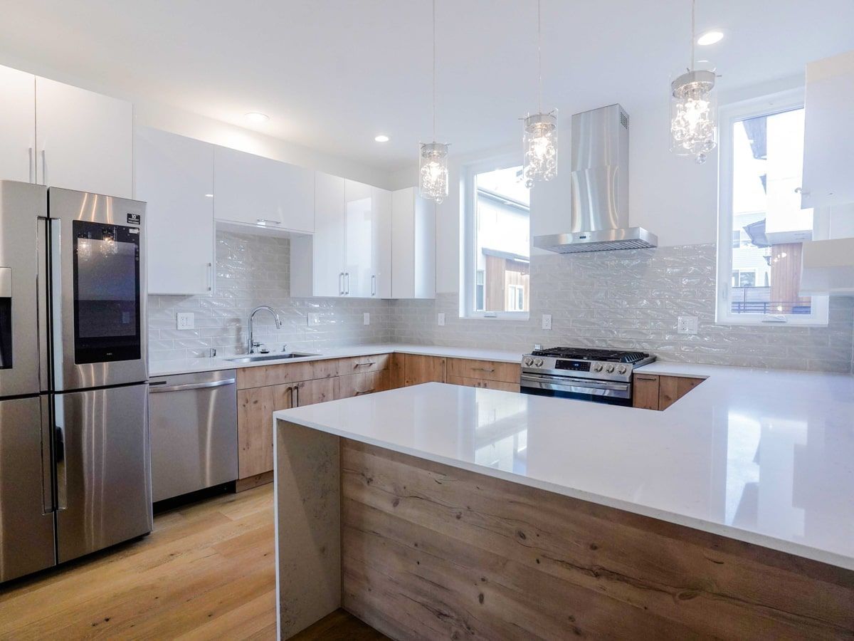 A kitchen with stainless steel appliances , wooden cabinets , and white counter tops.