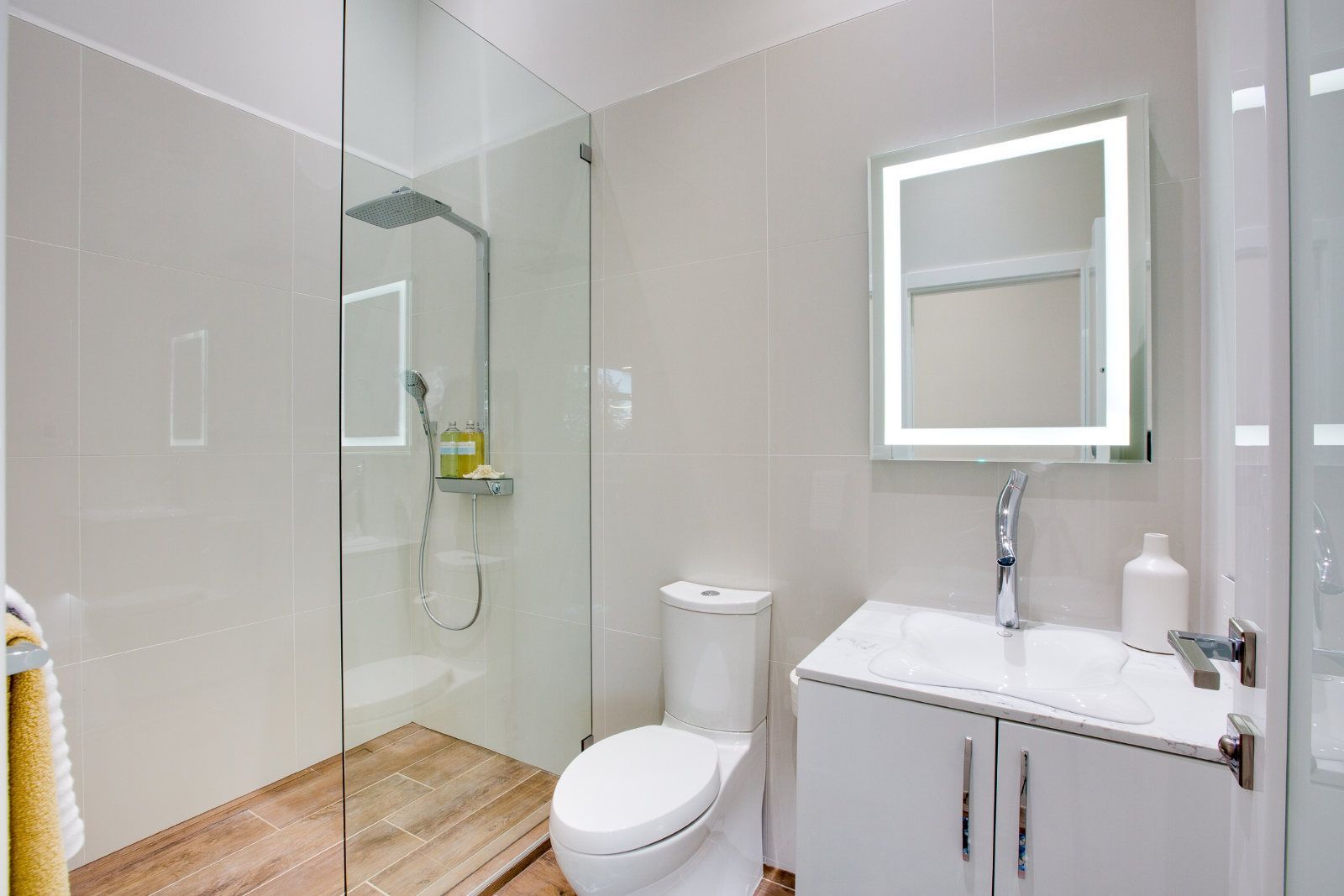 A bathroom with a toilet , sink , shower and mirror.